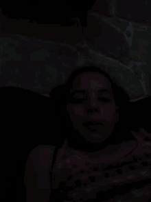 a young girl is laying on the floor in the dark with her eyes closed .