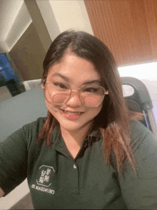 a woman wearing glasses and a green shirt with chinese writing on it smiles