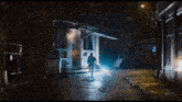 a man is walking down a street at night in front of a store called cleaner