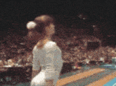 a pixelated image of a female gymnast performing a routine on a stage in front of a crowd .