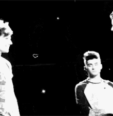 a couple of men are standing next to each other and holding hands .