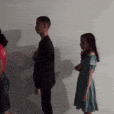 a girl in a green dress stands next to a man in a black suit