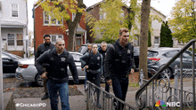 a group of police officers are walking down a sidewalk in front of a house .