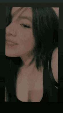 a woman with long black hair is wearing a black tank top .