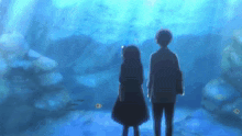 a man and a woman are standing in front of an aquarium