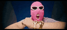 a person wearing a pink ski mask and sunglasses with their mouth open