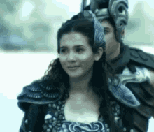 a woman in armor is standing next to a man in armor and a helmet .