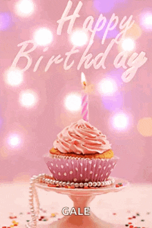a cupcake with a pink frosting and a lit candle with the name gale on it