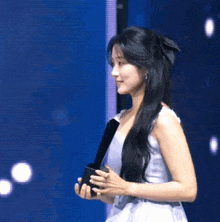 a woman in a white dress is holding a black object in her hands