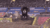 a batman monster truck is jumping over a dirt ramp