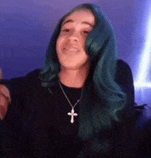 a woman with green hair wears a cross necklace