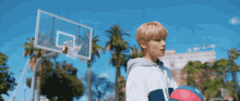 a young man holds a basketball in front of a basketball hoop