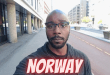 a man wearing glasses and a shirt that says norway takes a selfie