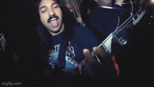 a man with long hair and a mustache is playing a jackson electric guitar .