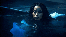 a woman in a white dress is swimming in a pool of water .