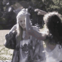 a woman wearing a shirt with a cat on it is standing next to another woman .