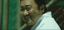a man with a beard wearing a white shirt smiles