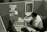 a man is sitting at a desk in front of a computer in a cubicle .