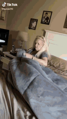 a woman is laying on a bed with a blanket and a tiktok watermark on the bottom right