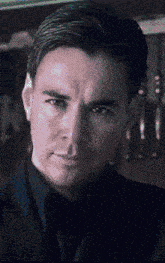 a man in a suit and tie is looking at the camera with a serious look on his face