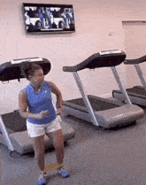 a woman is doing exercises on a treadmill while a tv is on the wall above her