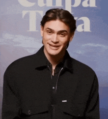 a young man in a black jacket is smiling in front of a sign that says ' tampa '