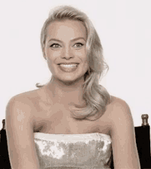 a woman in a strapless dress is sitting in a chair smiling .