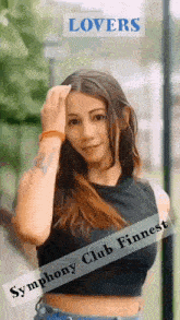 a woman in a black crop top is standing in front of a sign that says lovers symphony club finnest .