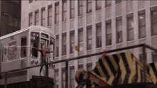 a man in a spiderman suit stands on top of a subway train