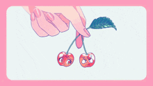 a woman 's hand is holding a pair of cherries with faces on them