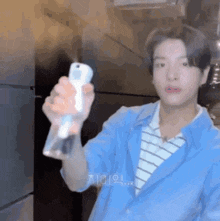 a young man in a blue jacket is holding a spray bottle .