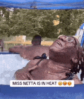 a woman in a bikini is laying in a hot tub with a caption that says miss netta is in heat