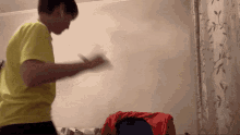 a man in a yellow shirt is dancing in front of a wall