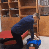 a man in a blue shirt is kneeling over a person in a blue bag that says " emergency " on it