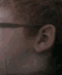 a close up of a person 's ear and glasses .