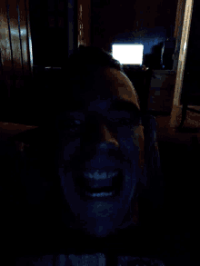 a person 's face is shown in a dark room with a light behind them