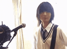 a young man is standing in front of a microphone and looking at the camera .
