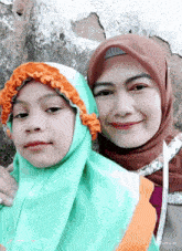 a woman wearing a hijab stands next to a little girl wearing a hijab