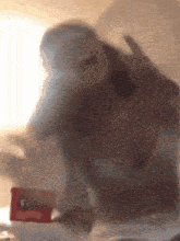 a blurred image of a person behind a glass with a box of gatorade in the background