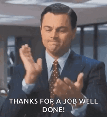 a man in a suit and tie is clapping his hands and saying thanks for a job well done !