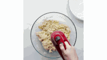 a person is mixing dough in a bowl with a red mixer .