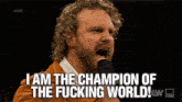 a man with curly hair is screaming into a microphone and saying i am the champion of the fucking world !