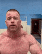 a shirtless man stands in front of a mirror in a gym