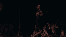 a man stands on a stage in front of a crowd with his hands on his hips