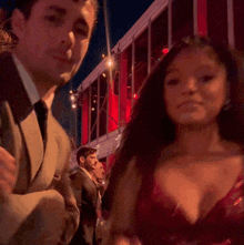 a woman in a red dress stands next to a man in a suit