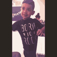 a young boy wearing a black born to rock t-shirt