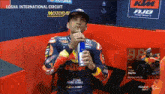 a man in a ktm jacket drinks from a red bull