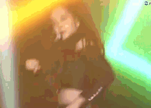 a woman in a black dress is dancing in front of a neon light .