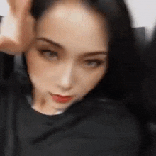 a woman with long black hair is wearing a black shirt and making a face .