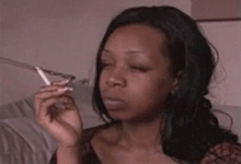 a woman is smoking a cigarette while sitting on a couch with her eyes closed